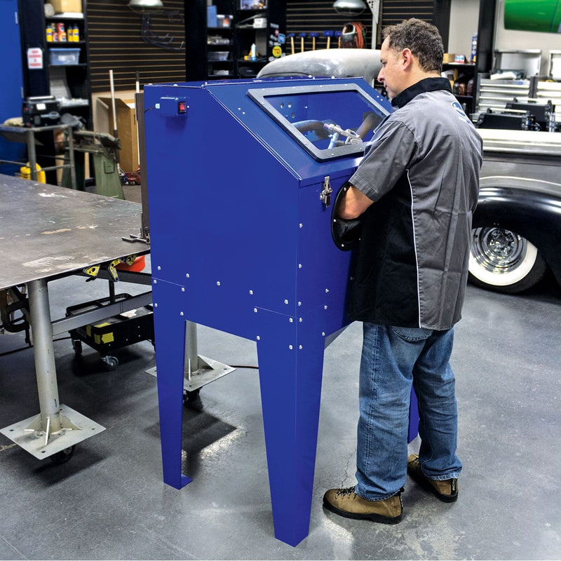Technician blasting a part inside the Eastwood B60 media blast cabinet in a shop