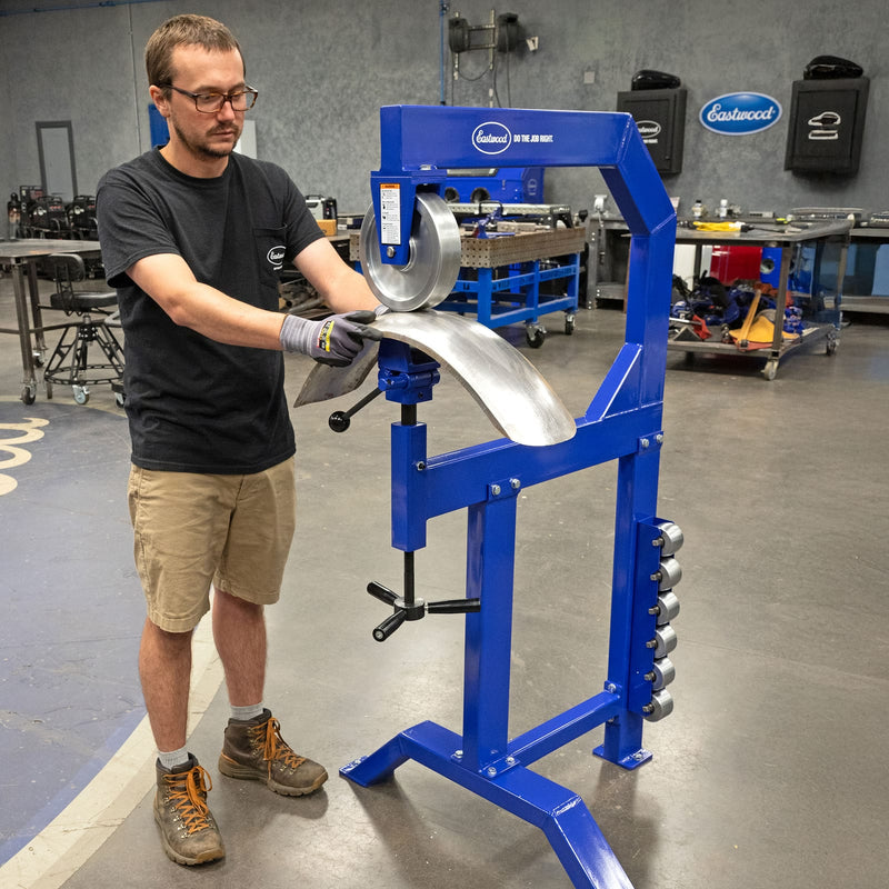 Fabricator forming a curved fender panel on the Eastwood English wheel and stand