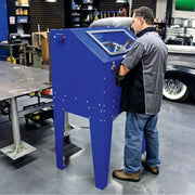 Technician blasting a part inside the Eastwood B60 media blast cabinet in a shop